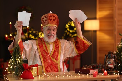 Photo of Saint Nicholas with letters at desk in room decorated for Christmas