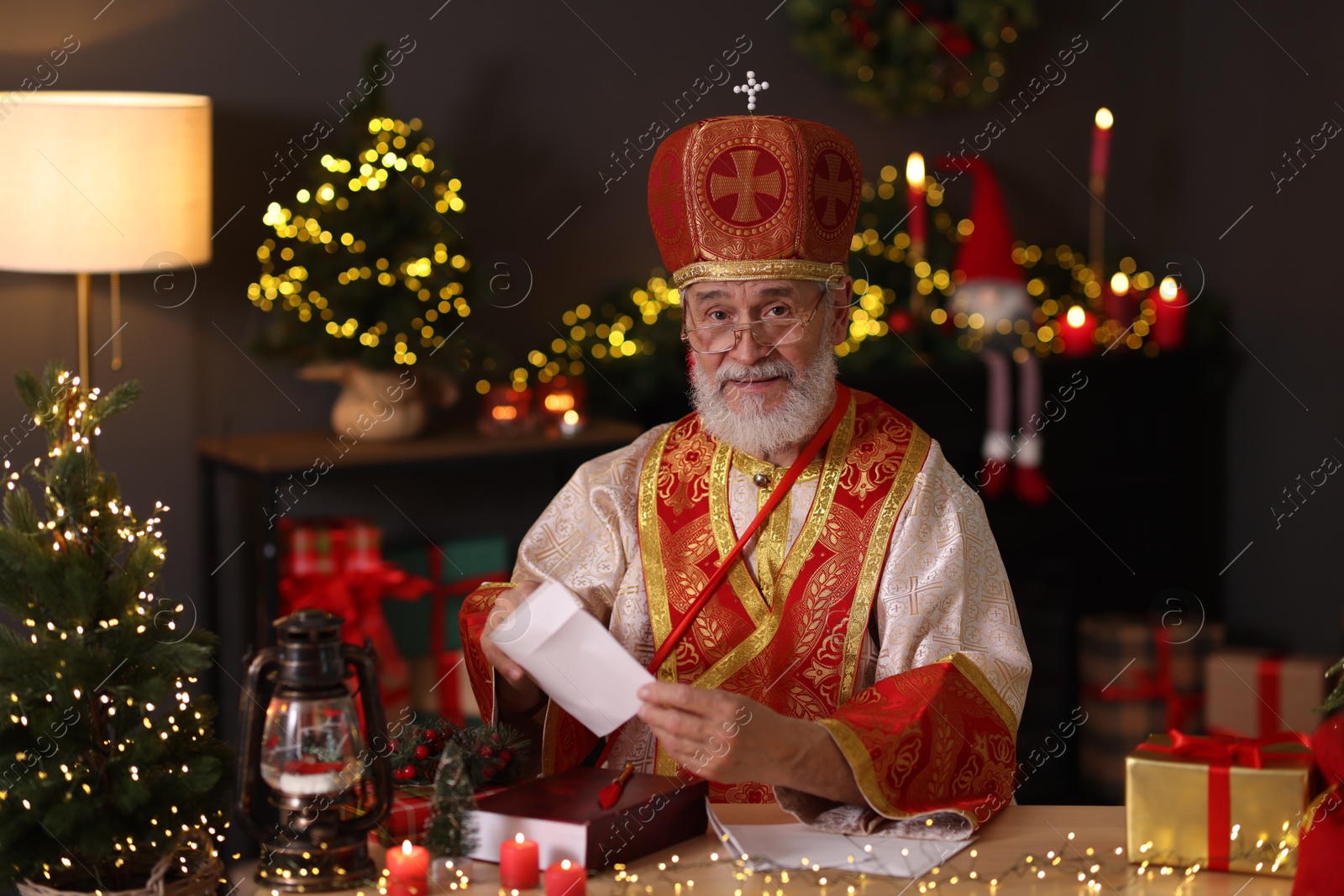 Photo of Saint Nicholas with letters at desk in room decorated for Christmas