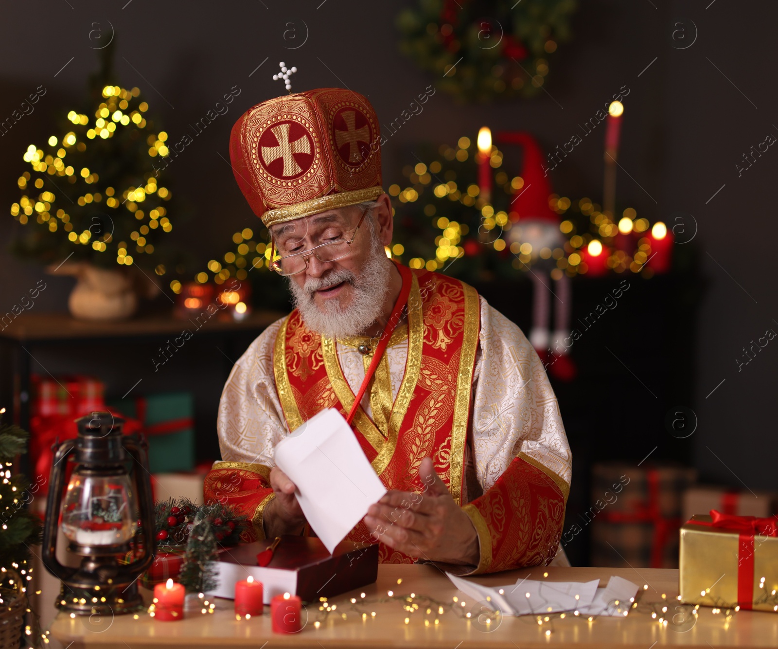 Photo of Saint Nicholas with letters at desk in room decorated for Christmas