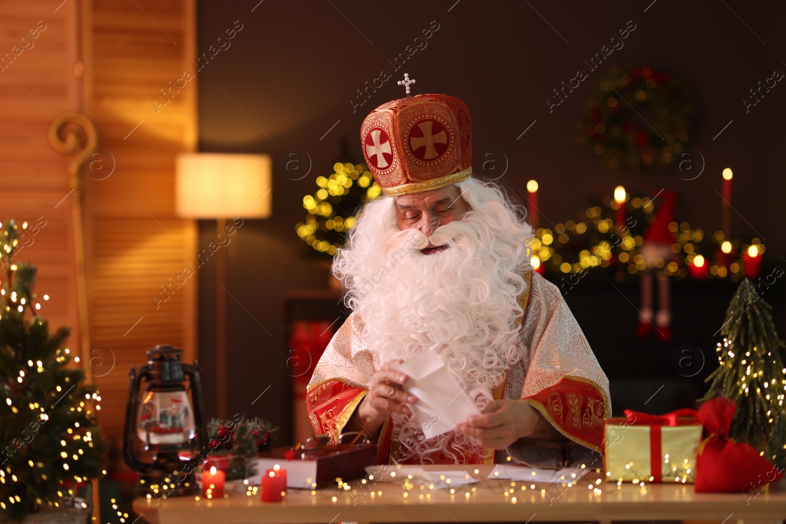 Photo of Saint Nicholas with letters at desk in room decorated for Christmas