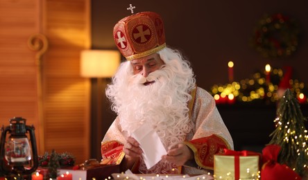 Photo of Saint Nicholas with letter at desk in room decorated for Christmas