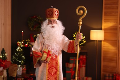 Photo of Saint Nicholas with gift in room decorated for Christmas