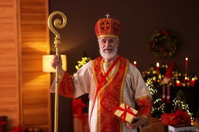 Photo of Saint Nicholas with gift in room decorated for Christmas