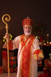 Photo of Saint Nicholas with gift in room decorated for Christmas