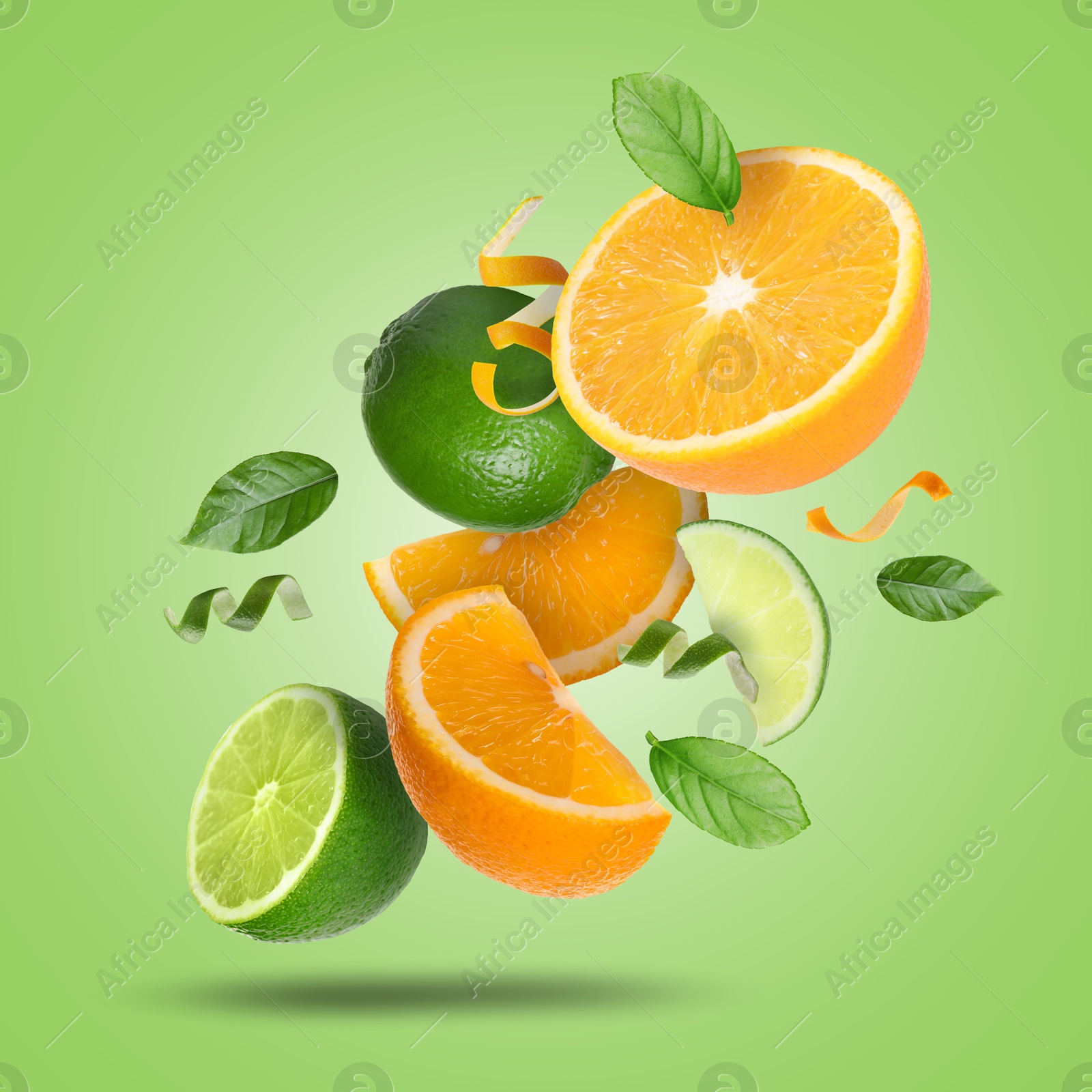 Image of Lime, orange, zest and leaves in air on light green background