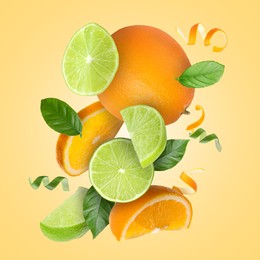 Image of Lime, orange, zest and green leaves in air on pale orange background