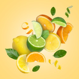 Image of Lime, lemon, orange, zest and green leaves in air on pale orange background