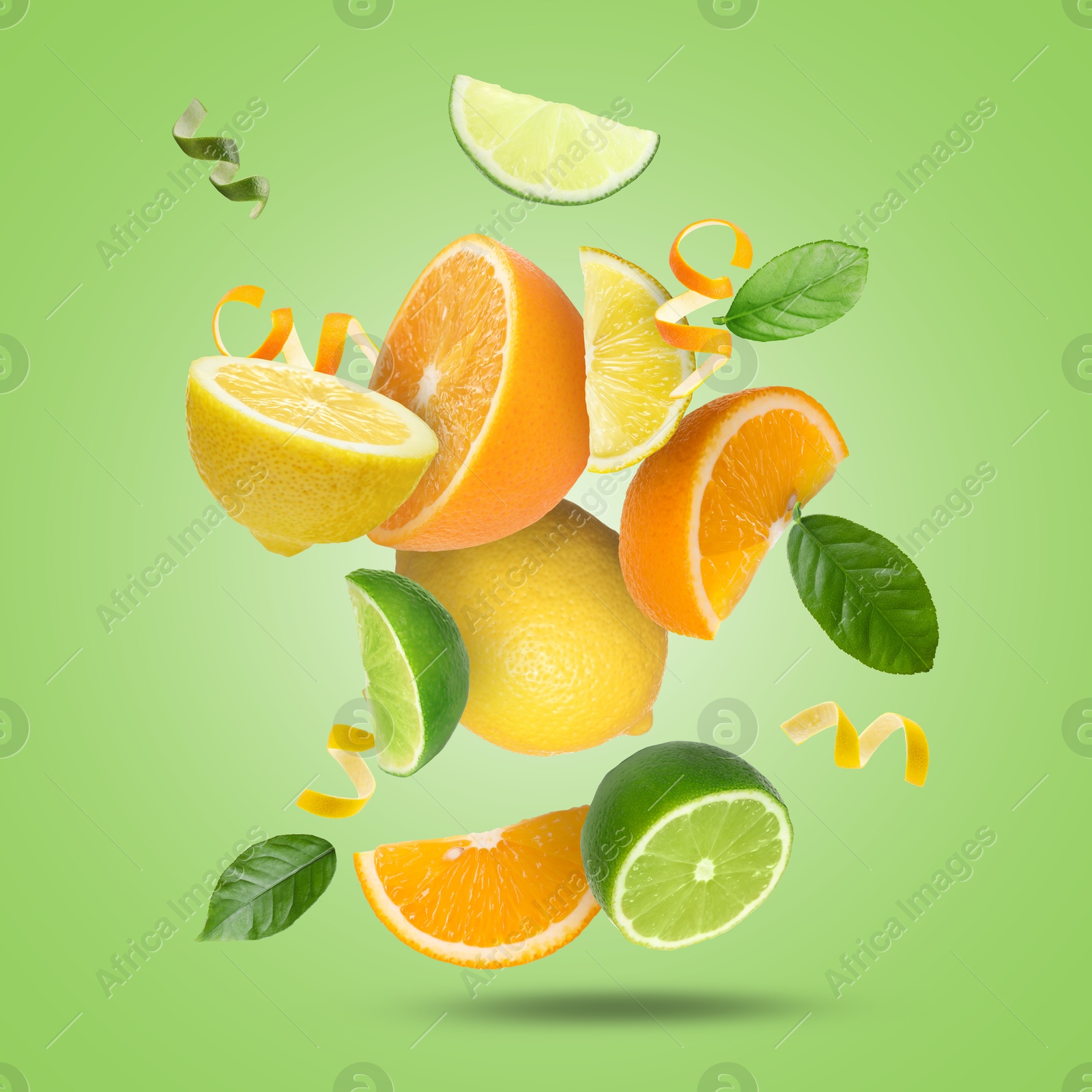 Image of Lime, lemon, orange, zest and leaves in air on light green background