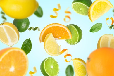 Image of Limes, lemons, oranges, zest and green leaves in air on light blue background