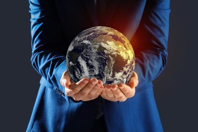 Image of Planet in our hands. Man holding Earth model on dark grey background, closeup