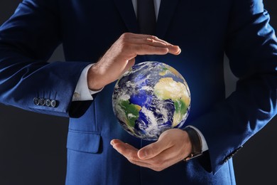 Image of Planet in our hands. Man holding Earth model on dark grey background, closeup