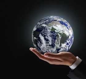 Image of Planet in our hands. Man holding glowing Earth on black background, closeup