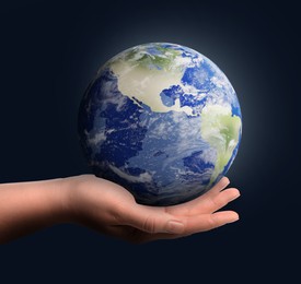 Image of Planet in our hands. Woman holding glowing Earth on dark blue background, closeup