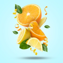 Image of Lemon, orange, zest and green leaves in air on light blue background