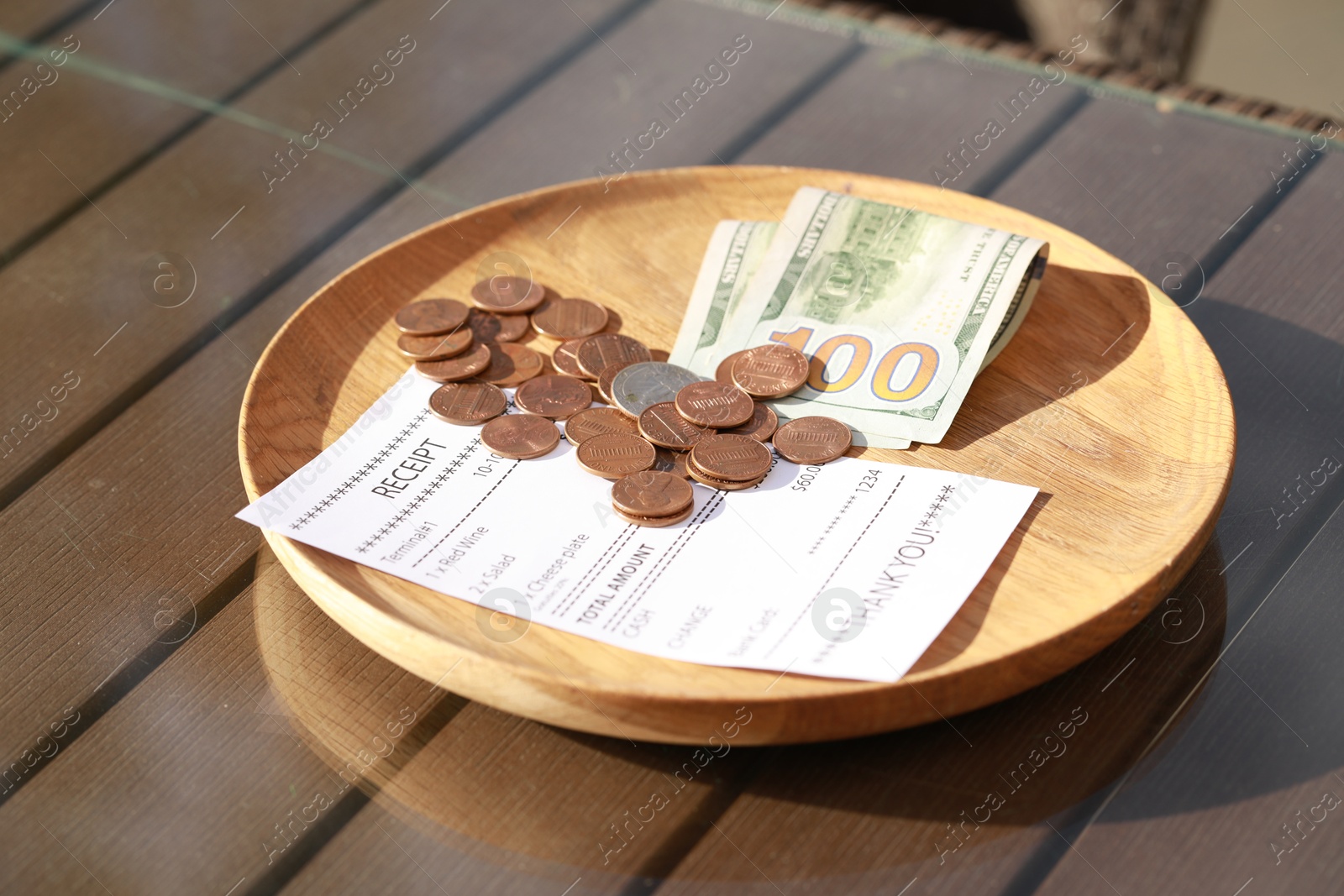 Photo of Wooden plate with payment for order and receipt on table, closeup. Leave tip