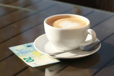 Photo of Tasty hot coffee and payment for order on table, closeup. Leave tip