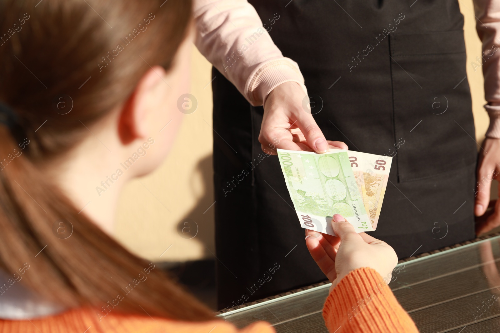 Photo of Woman paying for order to waitress at outdoor cafe, closeup. Leave tip