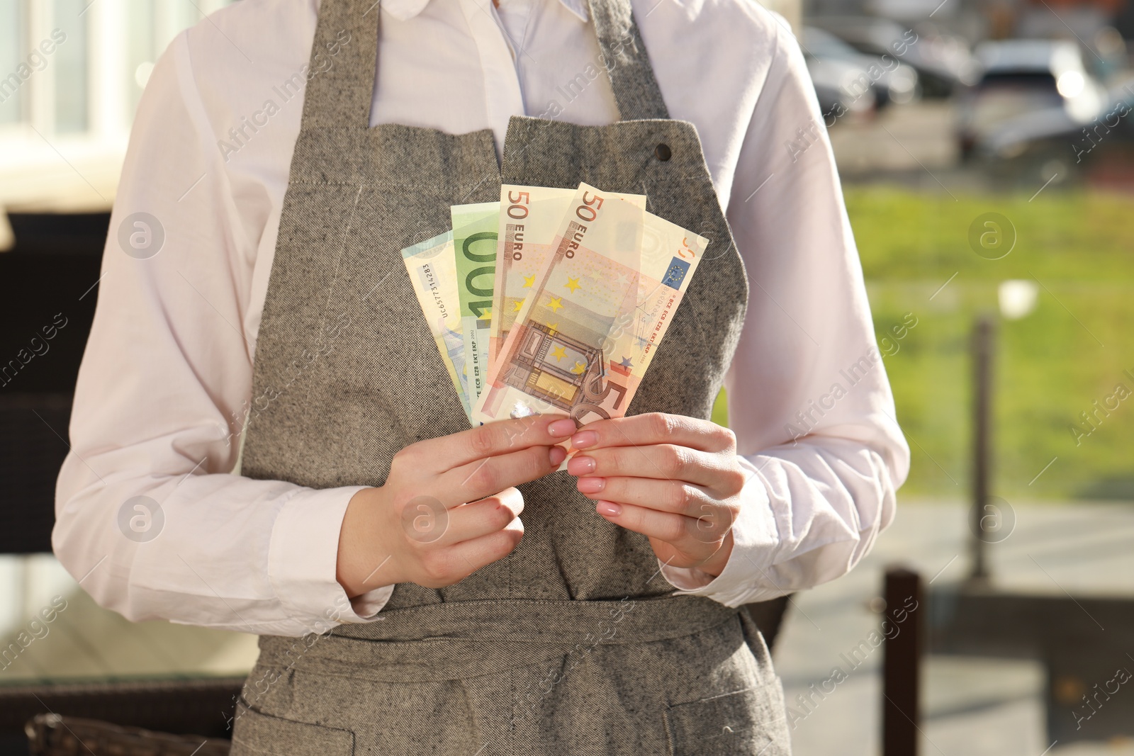 Photo of Waitress holding payment for order and tips at outdoor cafe, closeup