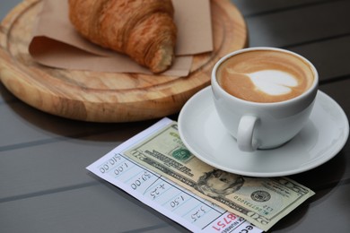 Photo of Croissant, coffee, tip and receipt on wooden table, closeup