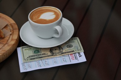 Photo of Coffee, tip and receipt on wooden table