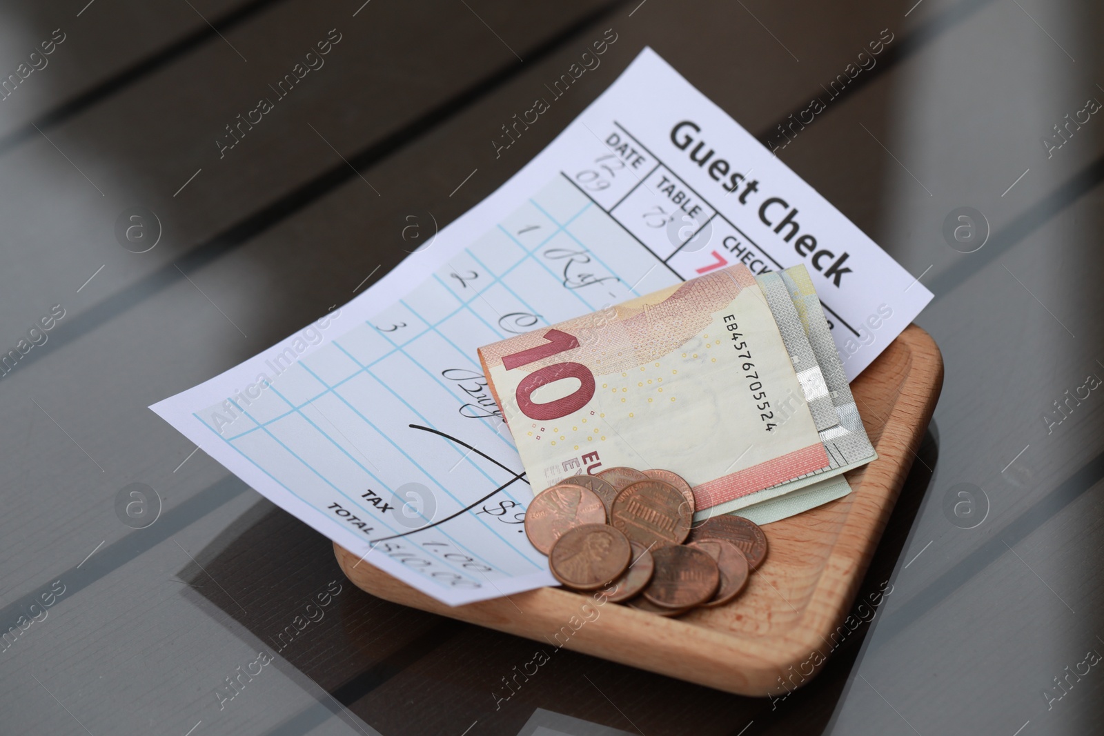 Photo of Tip and receipt on wooden table, closeup