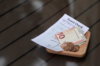 Photo of Tip and receipt on wooden table, closeup. Space for text