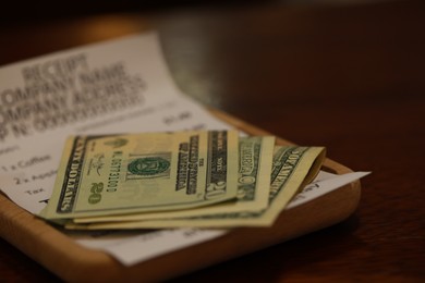 Photo of Tip and receipt on wooden table, closeup