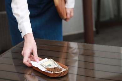 Photo of Waitress taking tips and payment for order from wooden table in cafe, closeup. Space for text