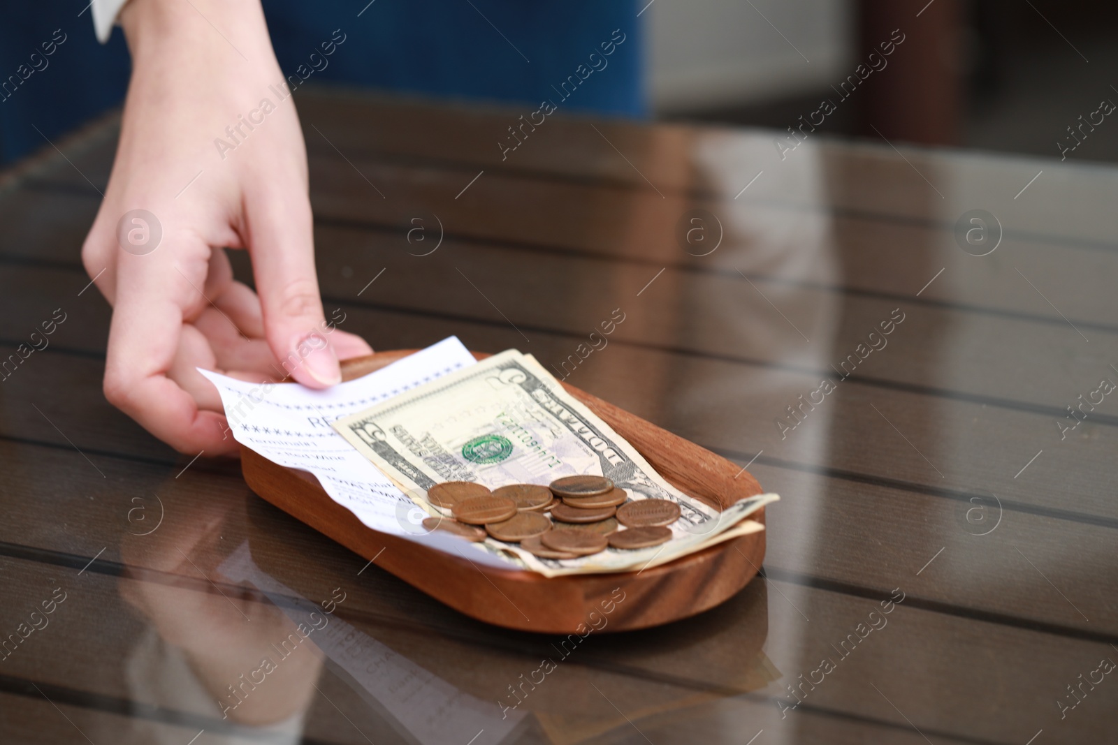 Photo of Waitress taking tips and payment for order from wooden table in cafe, closeup. Space for text