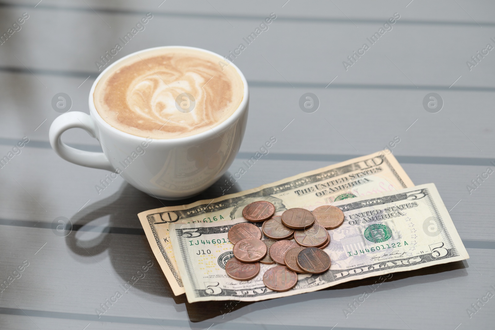 Photo of Tip and coffee on wooden table in outdoor cafe