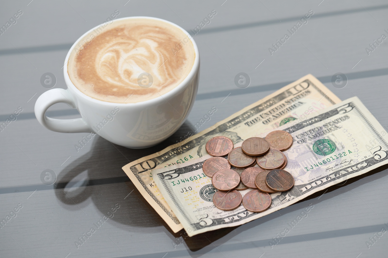 Photo of Tip and coffee on wooden table in outdoor cafe