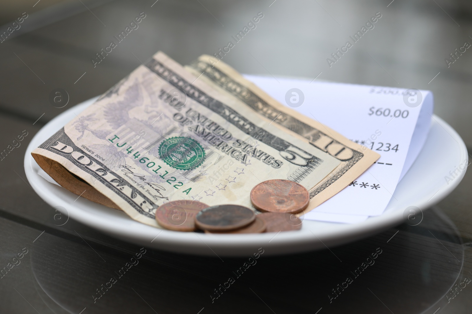 Photo of Tip and receipt on wooden table in cafeteria, closeup