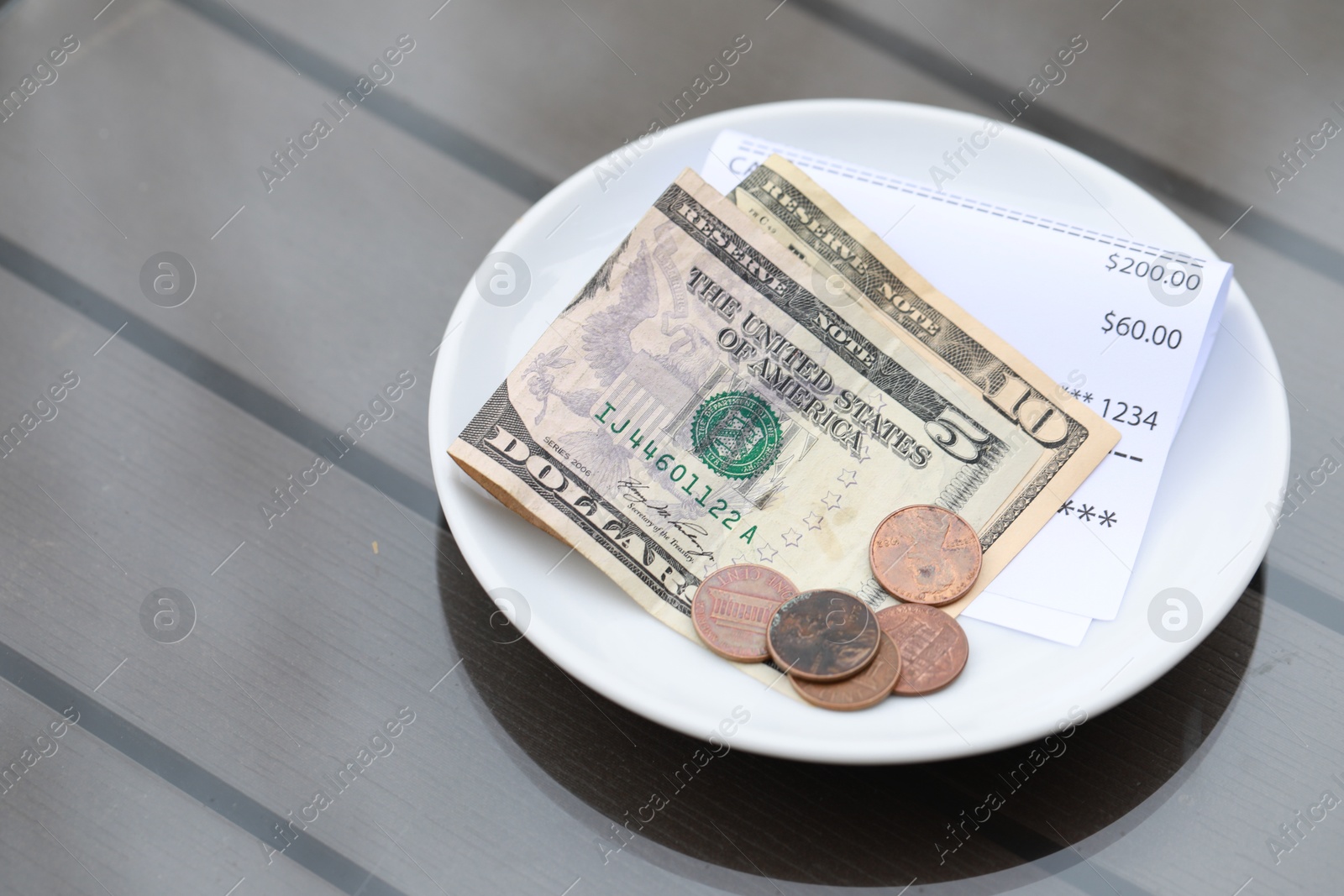 Photo of Tip and receipt on wooden table, closeup