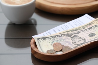 Photo of Tip, receipt and cup with coffee on wooden table, closeup