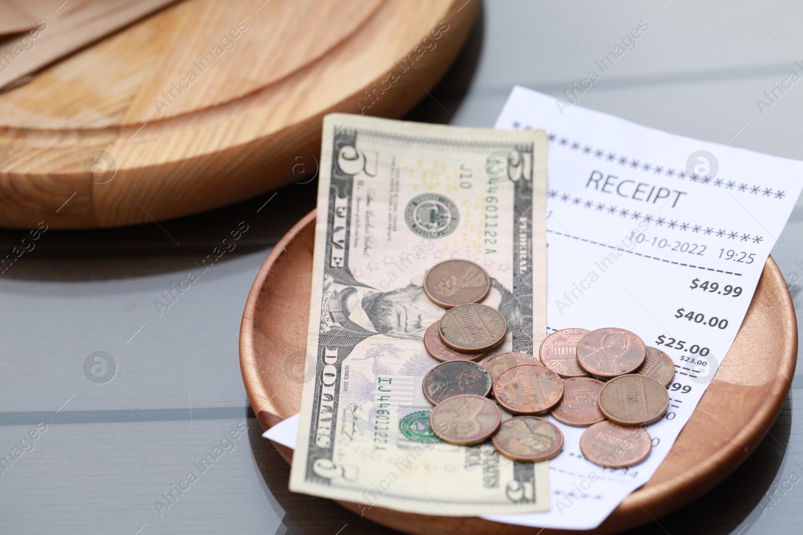 Photo of Tip and receipt on wooden table, closeup