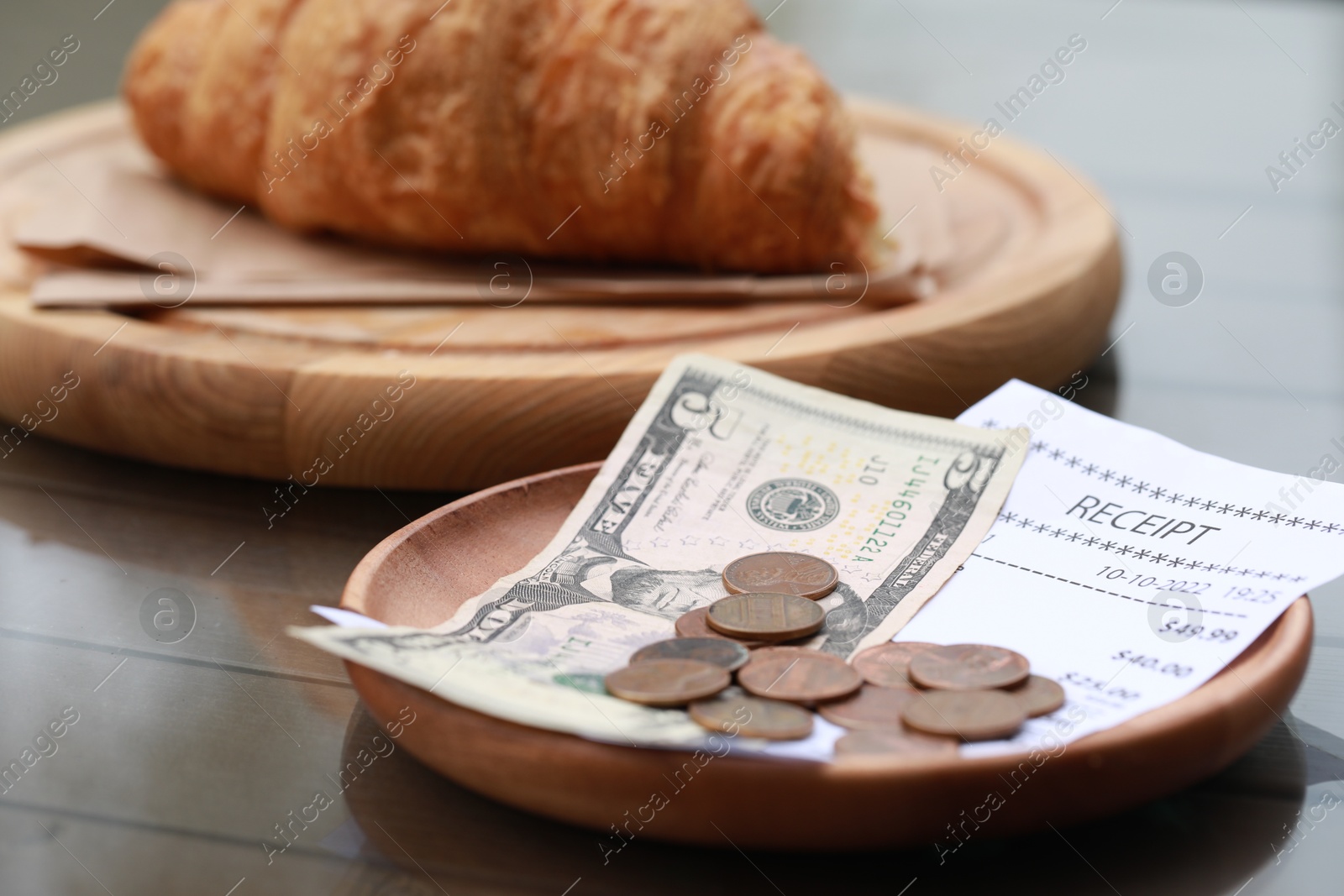 Photo of Tip, receipt and croissant on wooden table, closeup