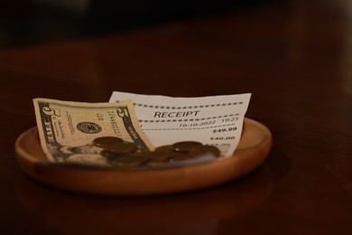 Photo of Tip and receipt on wooden table, closeup