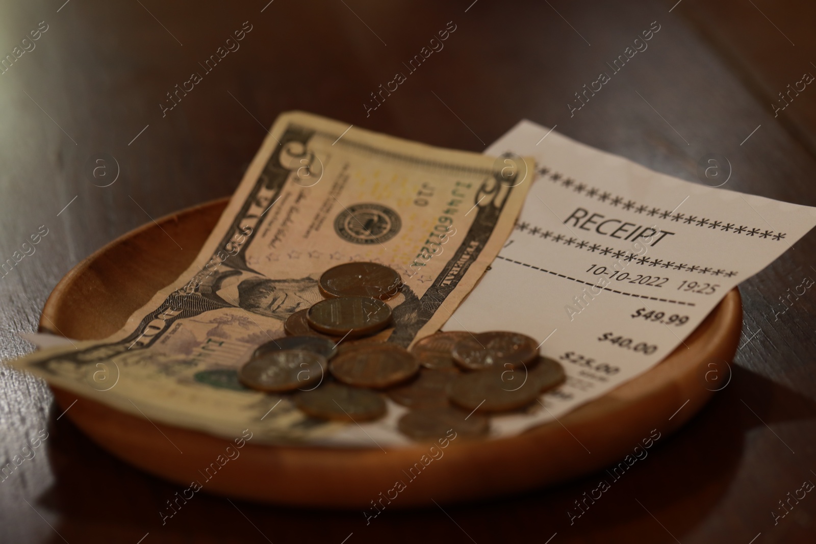 Photo of Tip and receipt on wooden table, closeup