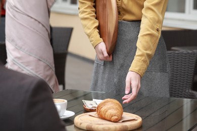 Photo of Waitress taking tips from wooden table in outdoor cafe, closeup