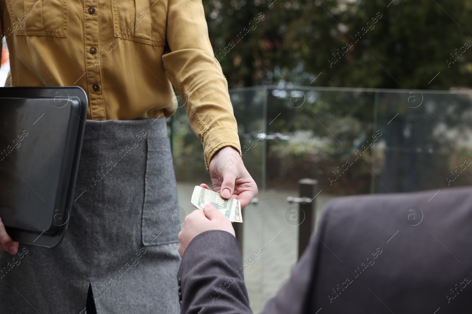 Photo of Client giving tips to waitress in outdoor cafe, closeup