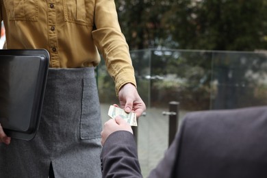 Photo of Client giving tips to waitress in outdoor cafe, closeup