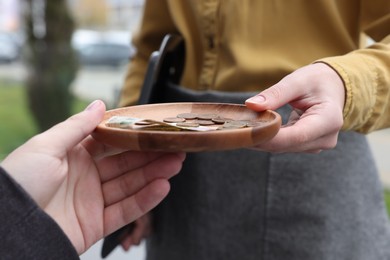 Photo of Client giving tips to waitress in outdoor cafe, closeup