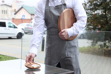 Photo of Waiter taking tips from wooden table in outdoor cafe, closeup