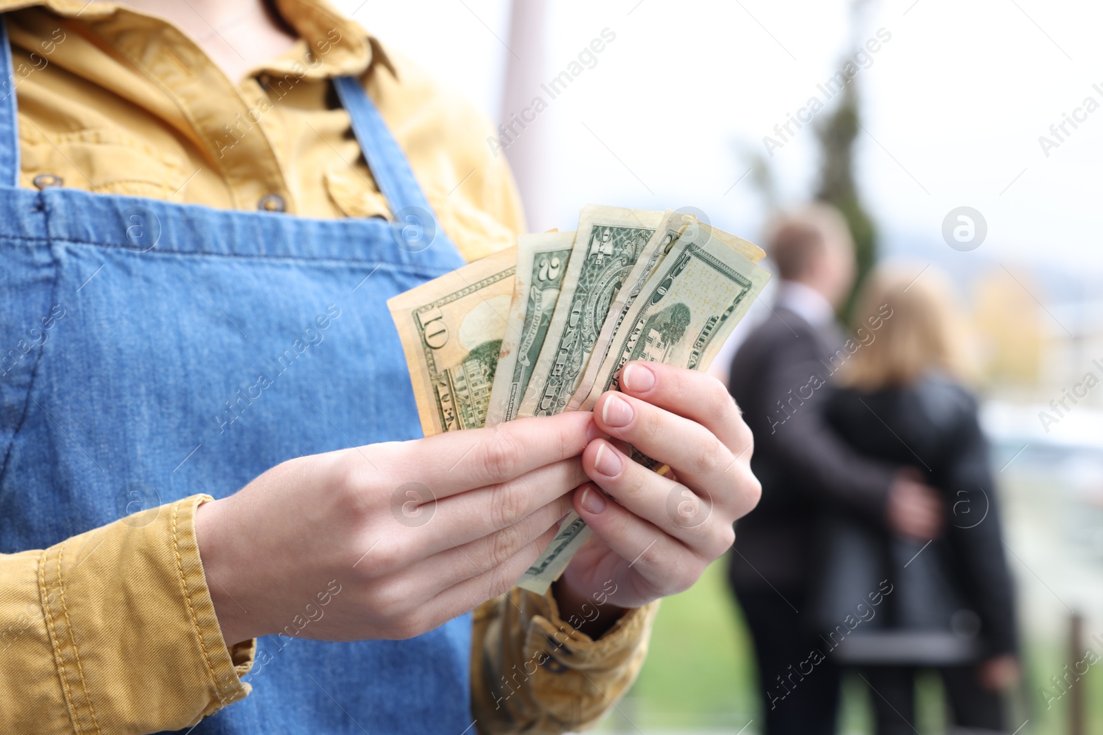 Photo of Waitress holding tips in outdoor cafe, closeup