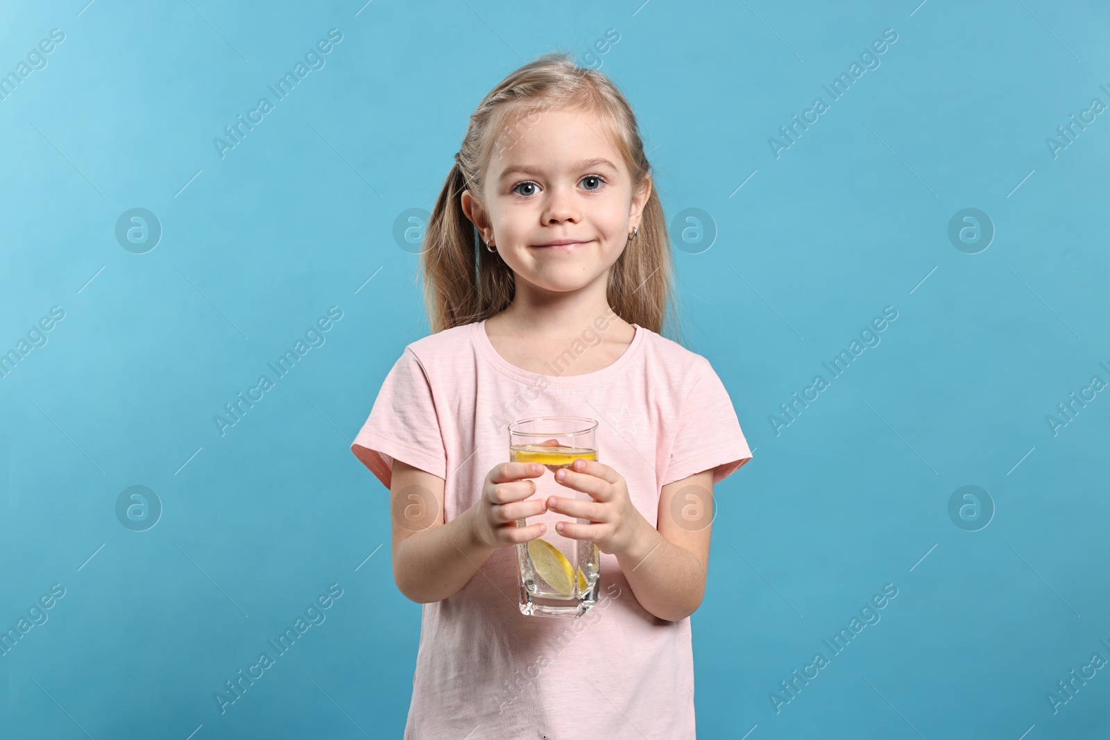 Photo of Girl with glass of lemonade on light blue background. Refreshing drink