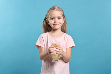 Photo of Girl with glass of lemonade on light blue background. Refreshing drink