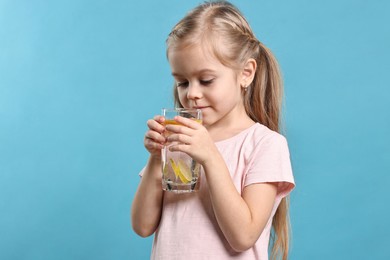 Photo of Girl with glass of lemonade on light blue background. Refreshing drink