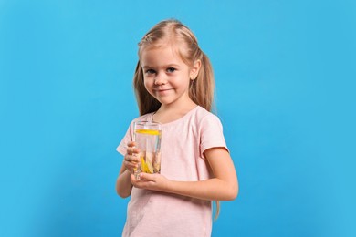 Photo of Girl with glass of lemonade on light blue background. Refreshing drink