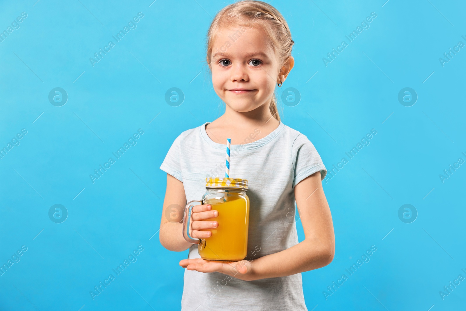 Photo of Girl with mason jar of orange juice on light blue background. Refreshing drink