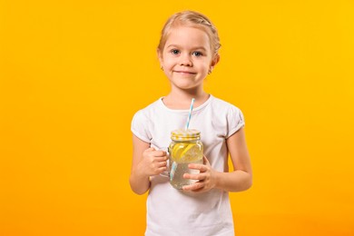 Photo of Girl with mason jar of lemonade on orange background. Refreshing drink